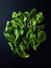 Heap of spinach on black background, top view