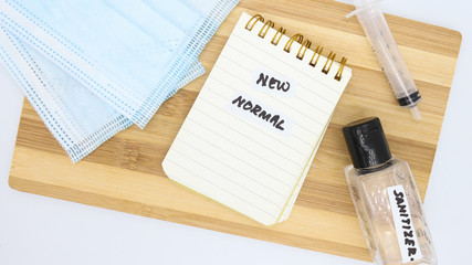New normal post COVID-19 concept. Image containing hand written note with face mask, bottle of hand...