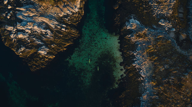 Aerial picture of kayaks between islands. Active summer vacation, north of norway located in lofoten islands. Two people kayaking surrounded beautiful landscape and turquoise sea. Distance picture