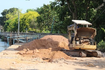 Backhoe excavator is under road construction. River bank Samut Songkhram province in Thailand, 15 May 2020