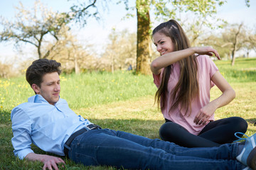 Obraz premium Girlfriend beating her boyfriend for fun on a meadow with yellow flowers, in the background trees