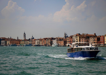 A view of Venice shore with a tourist ferry on the foreground on the late summer afternoon.