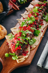 Lula Kebab on the wooden service plank with garnet and arabic bread