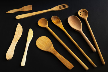 Old wooden kitchen set, wooden spoon, wooden fork, spatula and more on a black background