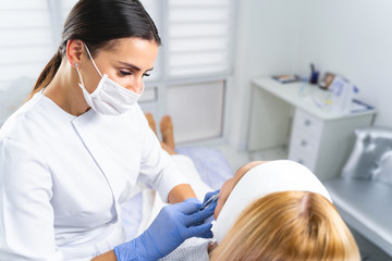 Dermatologist in a face mask treating a woman