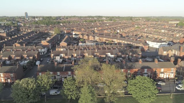 Drone aerial view above generic British housing estate community at sunrise dolly right low angle