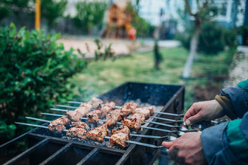 a man fries kebabs on the grill in his infield.