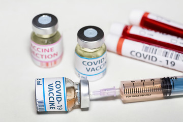 Vaccine bottle with hypodermic injection needle with medicinal drugs and blood sample vials at a lab clinic used for detection and treatment of coronavirus patients