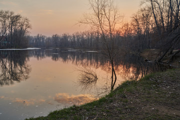    Early spring. Morning dawn over the lake in a misty, thoughtful haze. Beautiful view of the forest covered with fog early in the morning. The sun's rays of light.       