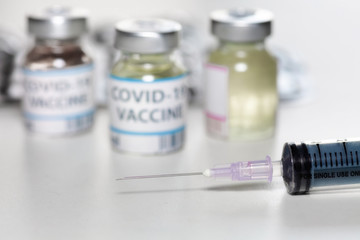 Injection syringe with vaccine bottles and medicine in selective focus for treatment of Coronavirus patients