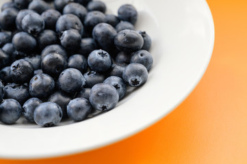 Natural looking blueberries in white plate. Selective focus.