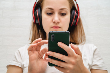 Fototapeta premium Young smiling woman listening to the music, through headphones on her head