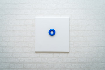 blue donut circle on white canvas against a white brick wall