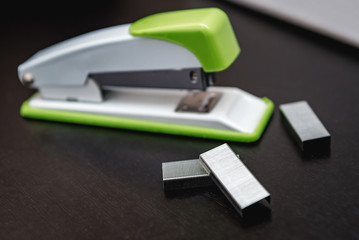 Green stapler on a black background