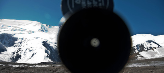 View of a group of climbers through a magnifying glass telescope. Scenic landscape of snowy mountain peaks.