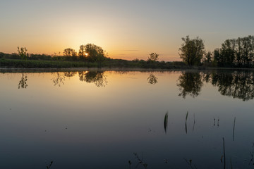 Dawn over the lake. Beautiful evening blue sky at sunset with flaming bright light clouds. Warm summer evening at sunset. May.
