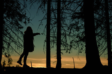 Silhouette of a woman dancing in the forest during sunset/sunrise.