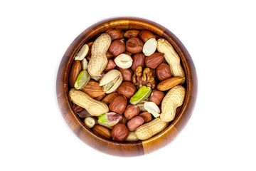 Top view of different nuts mix: almonds, pistachios, peanuts, hazelnuts heap in round brown wooden bowl isolated on white background.