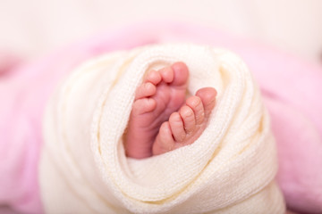 Close up of tiny adorable bare pink baby feet as the infant sleeps on white blanket.