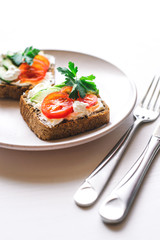 Avocado toast with cherry tomatoes and feta cheese on plate.