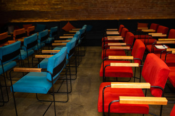 Fototapeta premium Red and blue chairs in the dark hall of a small cinema