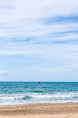 landscape with sea, beach, blue sky and  small white ship in distance, sunny day in Mediterranean