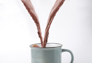 Closeup of flowing hot cocoa drink into the mug.Splashing of hot chocolate beverage