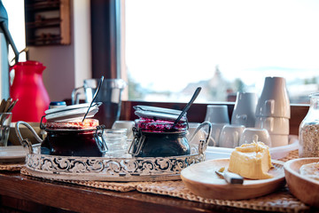 A breakfast buffet with homemade jams and butter at mountain cabin during sunrise.
