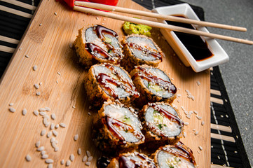 Fried rolls with cucumbers and chicken.
Wood background. White cup with sauce. Chinese chopsticks