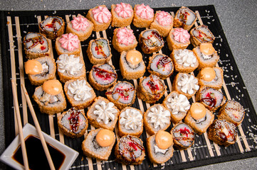 Seth rolls on a black background. Photo for the menu. A cup with sauce. Chinese chopsticks