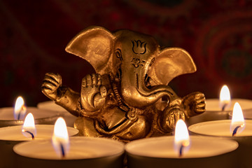 Close up of golden Ganesha sculpture illuminated by tea lights. Still life with golden elephant...