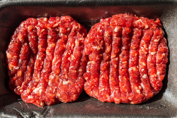 Raw Beef Burgers In A Packaging Tray.