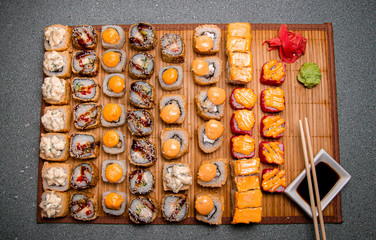 Set of baked rolls on a brown tray. Photo for the menu. A cup with sauce. Chinese chopsticks