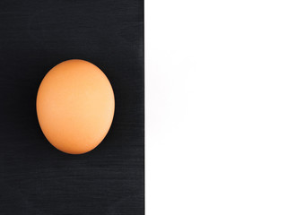 Brown egg on a black wooden and white background. Healthy eating concept