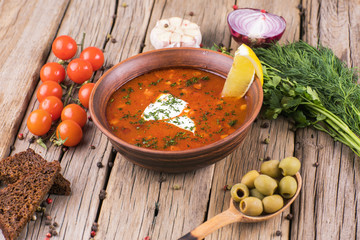 Dish of russian hodgepodge soup and other food on a wooden table.