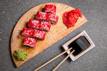 Rolls with red caviar on a wooden stand. Photo for the menu. Chinese sticks