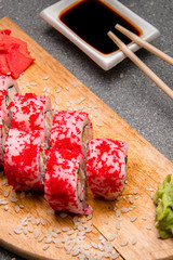 Rolls with red caviar on a wooden stand. Photo for the menu. Chinese sticks