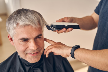 Obraz na płótnie Canvas Mature man getting hairdo with special equipment
