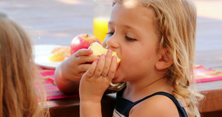 Little girl biting apple eating fruit outside