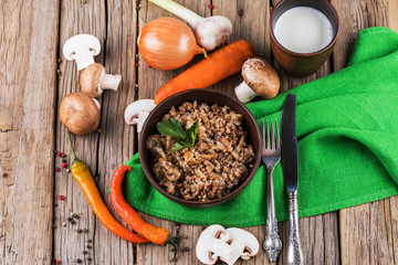 Buckwheat porridge with mushrooms in the frying pan on the table