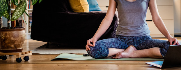 woman doing yoga workout at home watching videos online on laptop computer