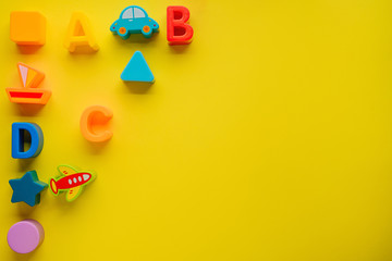 Top view on children s toys on a yellow background. Children's toys on the table. concept for advertising toys for children. Copy space children's toy.