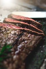 Close-up of beefsteak slices cooked on the grill. Spiced with rosemary and coarse salt. Soapstone surface. Vertical shot