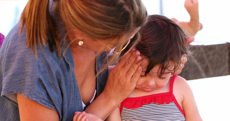 Mom applying sunscreen to upset child feeling angr