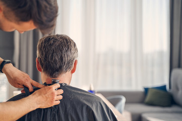 Fototapeta premium Brunette male cutting hair with special equipment