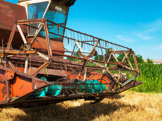 Wheat harvesting in the summer. Red harvester working in the field. Golden ripe wheat harvest...