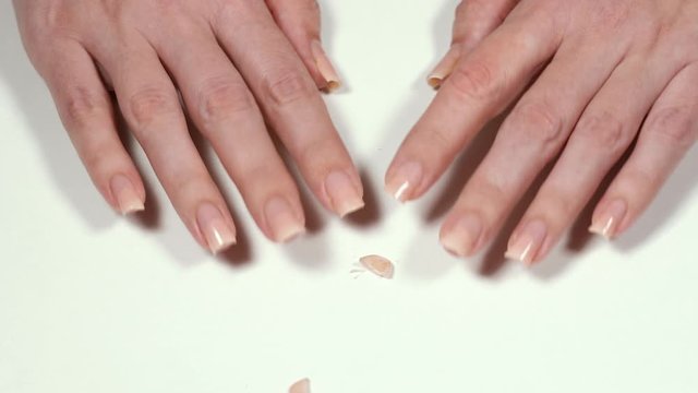 Closeup view video footage of woman have to cut her long manicured painted nails staying home while all beauty salons closed because of quarantine. Cutted female painted nails isolated on white table.