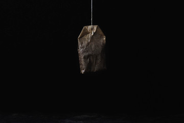 One used tea bag weighs on a black background
