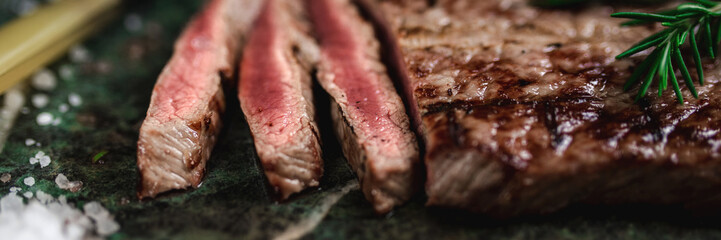 Close-up macro view of sliced beefsteak, raw and juicy in the middle. Cooked on the grill. Horizontal. Banner.