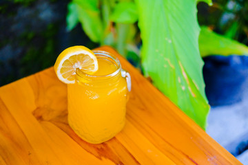 fresh cold drink orange syrup over ice cubes, isolated on a wooden background. Making orange...